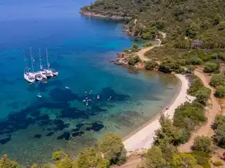 Ιστιοπλοϊκά δεμένα μαζί σε ήσυχο όρμο κοντά στο Πόρτο Καρράς, με επιβάτες να κολυμπούν