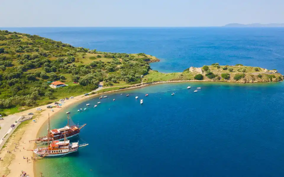 Sandy bay with two wooden boats near the shore and a green headland