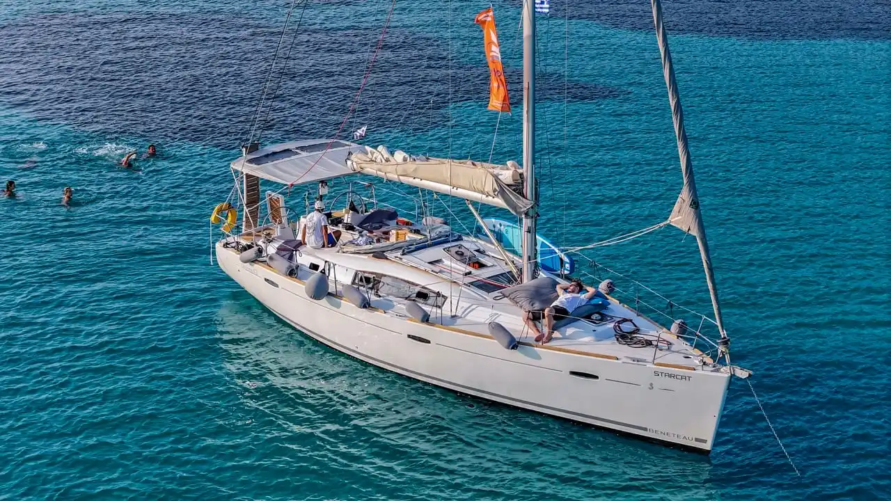 Guests swimming from a sailing yacht at anchor in bright turquoise water
