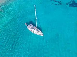 Ιστιοπλοϊκό μόνο του στην άγκυρα σε φωτεινά τιρκουάζ νερά, από ψηλά