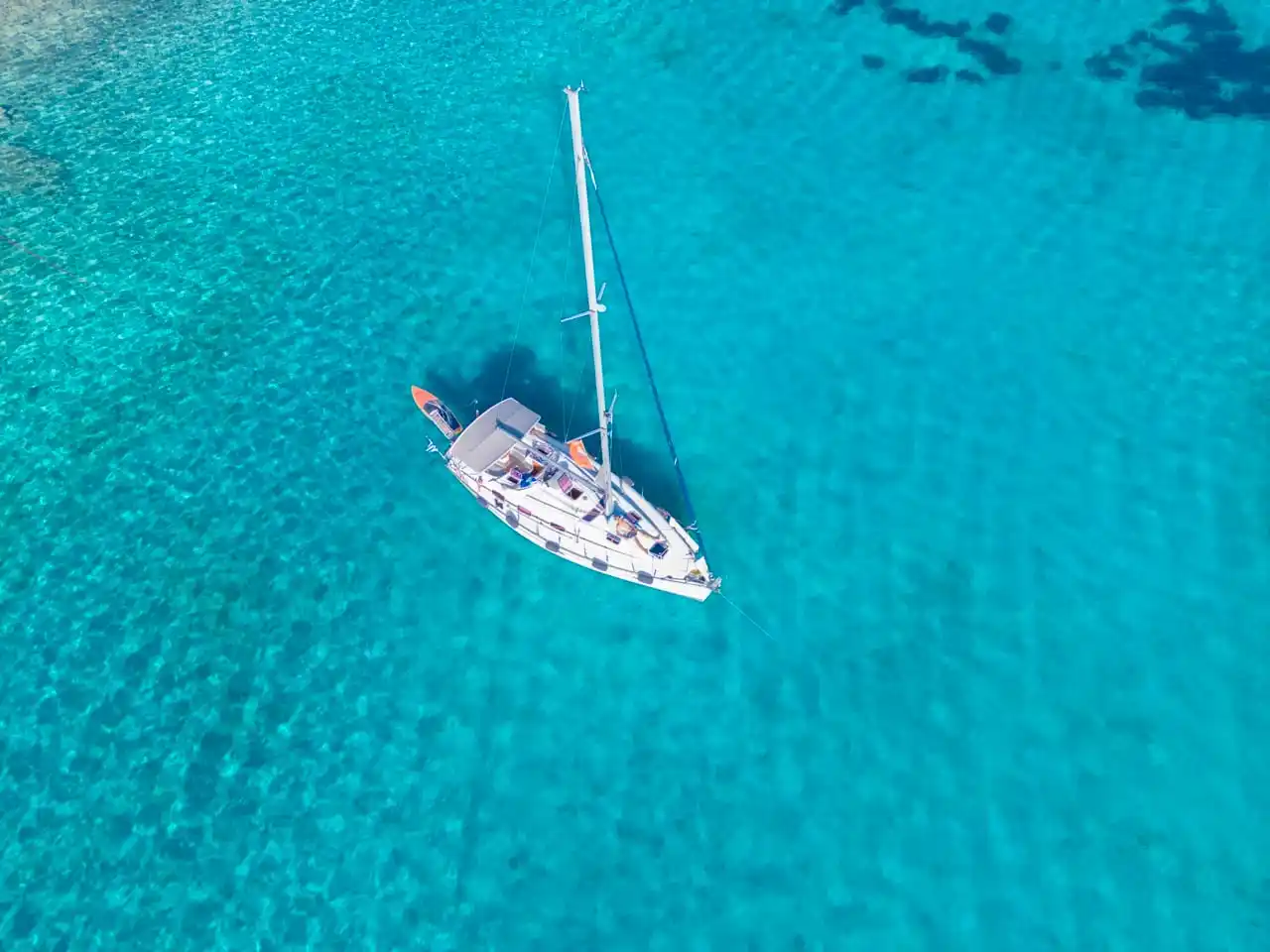 Ιστιοπλοϊκό μόνο του στην άγκυρα σε φωτεινά τιρκουάζ νερά, από ψηλά