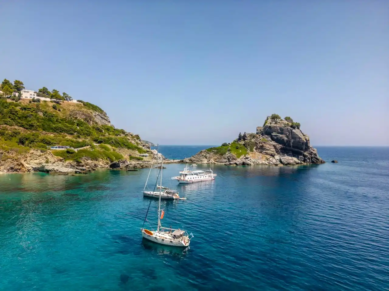 Sailing yachts anchored off the rock of Agios Ioannis on Skopelos