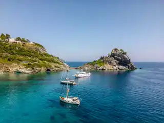 Sailing yachts anchored off the rock of Agios Ioannis on Skopelos