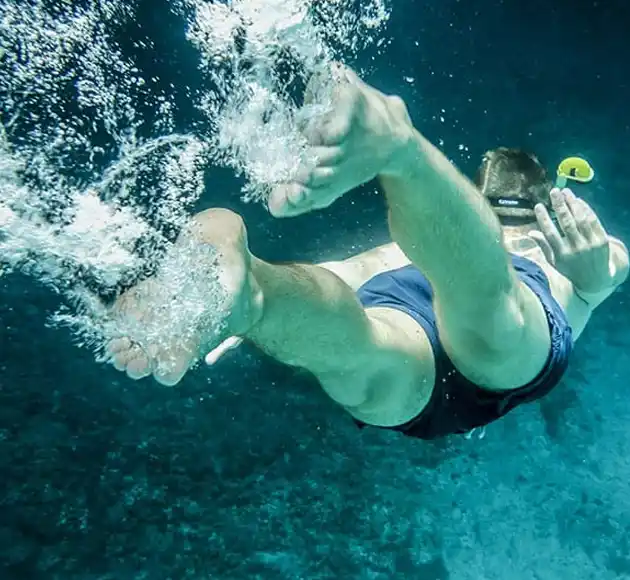 Swimmer diving underwater in clear blue water