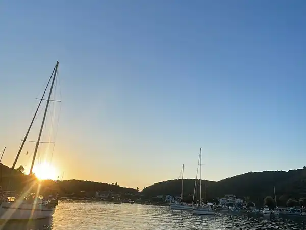 Sun setting behind sailing yachts moored in a calm harbour