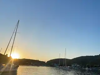 Sun setting behind sailing yachts moored in a calm harbour
