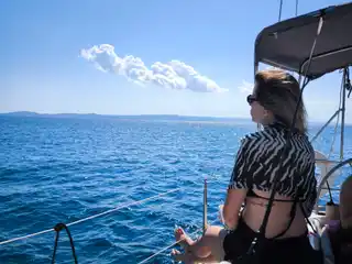 Γυναίκα κάθεται στην πλώρη ιστιοπλοϊκού και κοιτάζει τη θάλασσα
