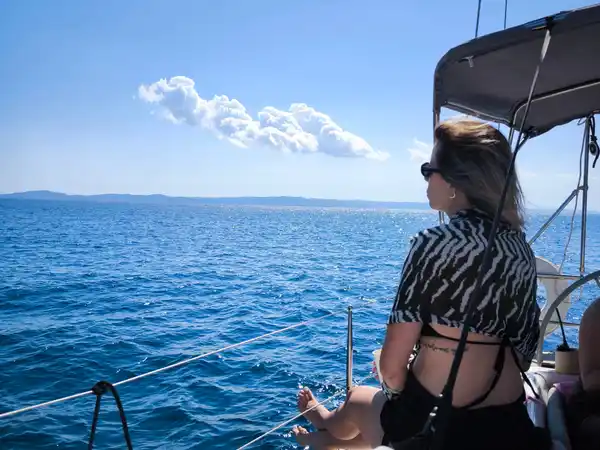 Γυναίκα κάθεται στην πλώρη ιστιοπλοϊκού και κοιτάζει τη θάλασσα