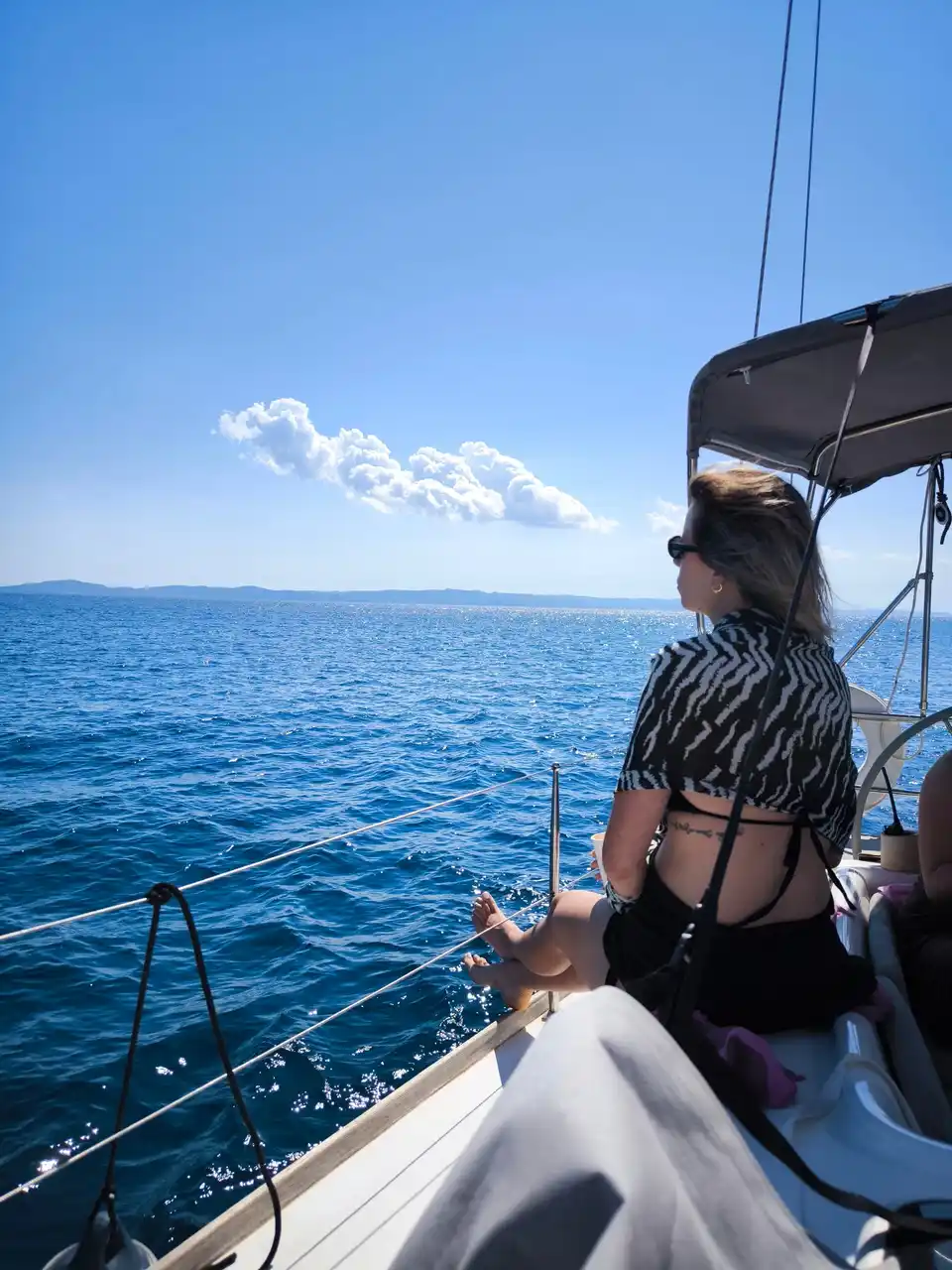 Γυναίκα κάθεται στην πλώρη ιστιοπλοϊκού και κοιτάζει τη θάλασσα