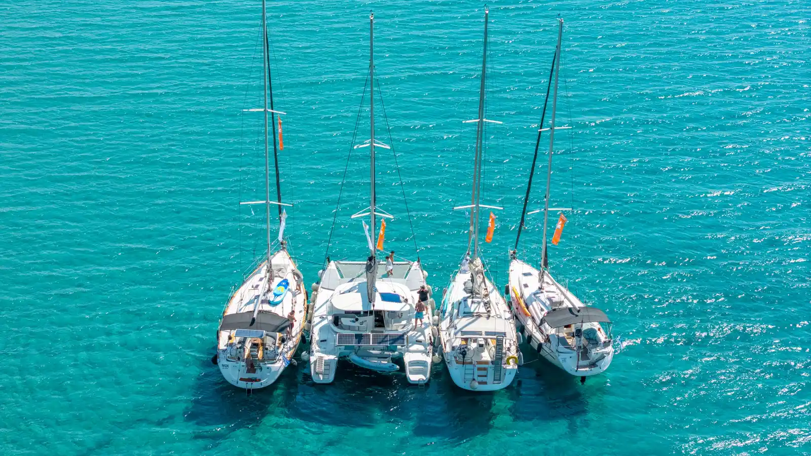 Three sailing yachts and a catamaran moored side by side, seen from above